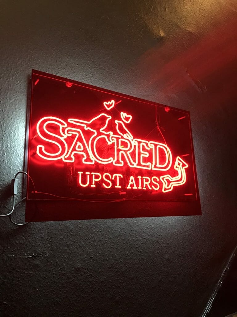 Red neon Sacred Gin sign with birds on Sacred Gin at The Star Highgate