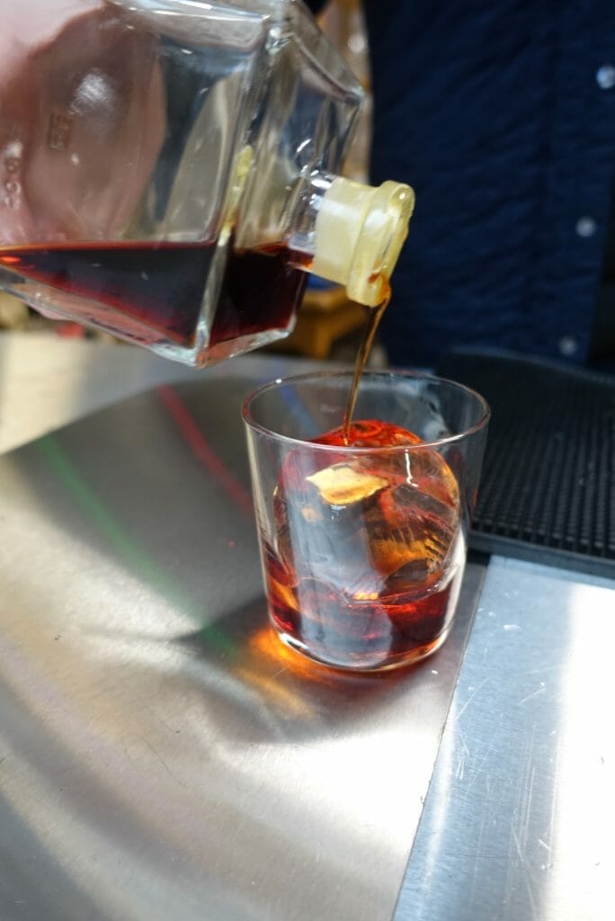 Pouring bottled negroni into the glass with hand cut ice