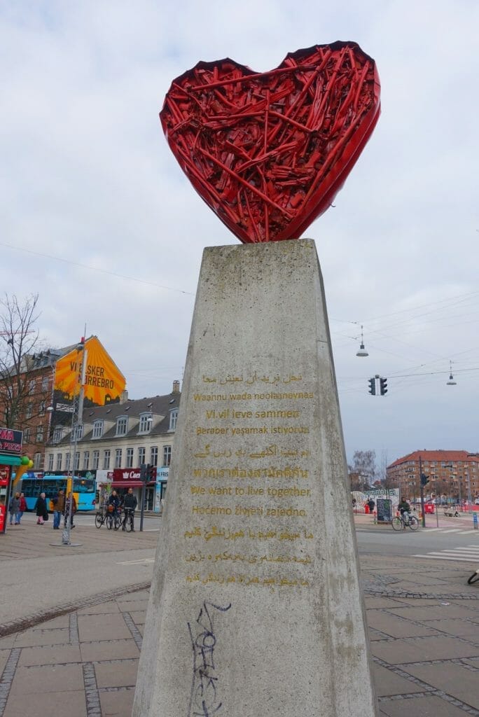 Statue of a red heart with 'We want to live together' in all the languages of the local people on it