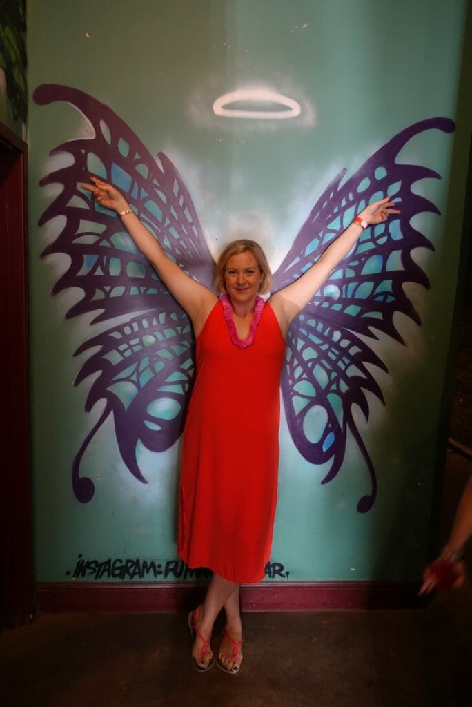 Katie in front of a wall with wings painted on it