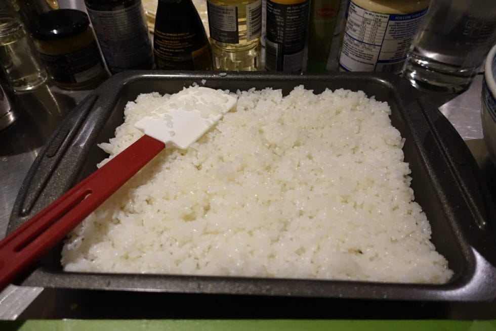 Rice spread out on the baking sheet to cool down