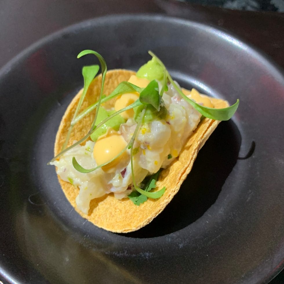 Small taco with seabream ceviche inside and garnished with microherbs