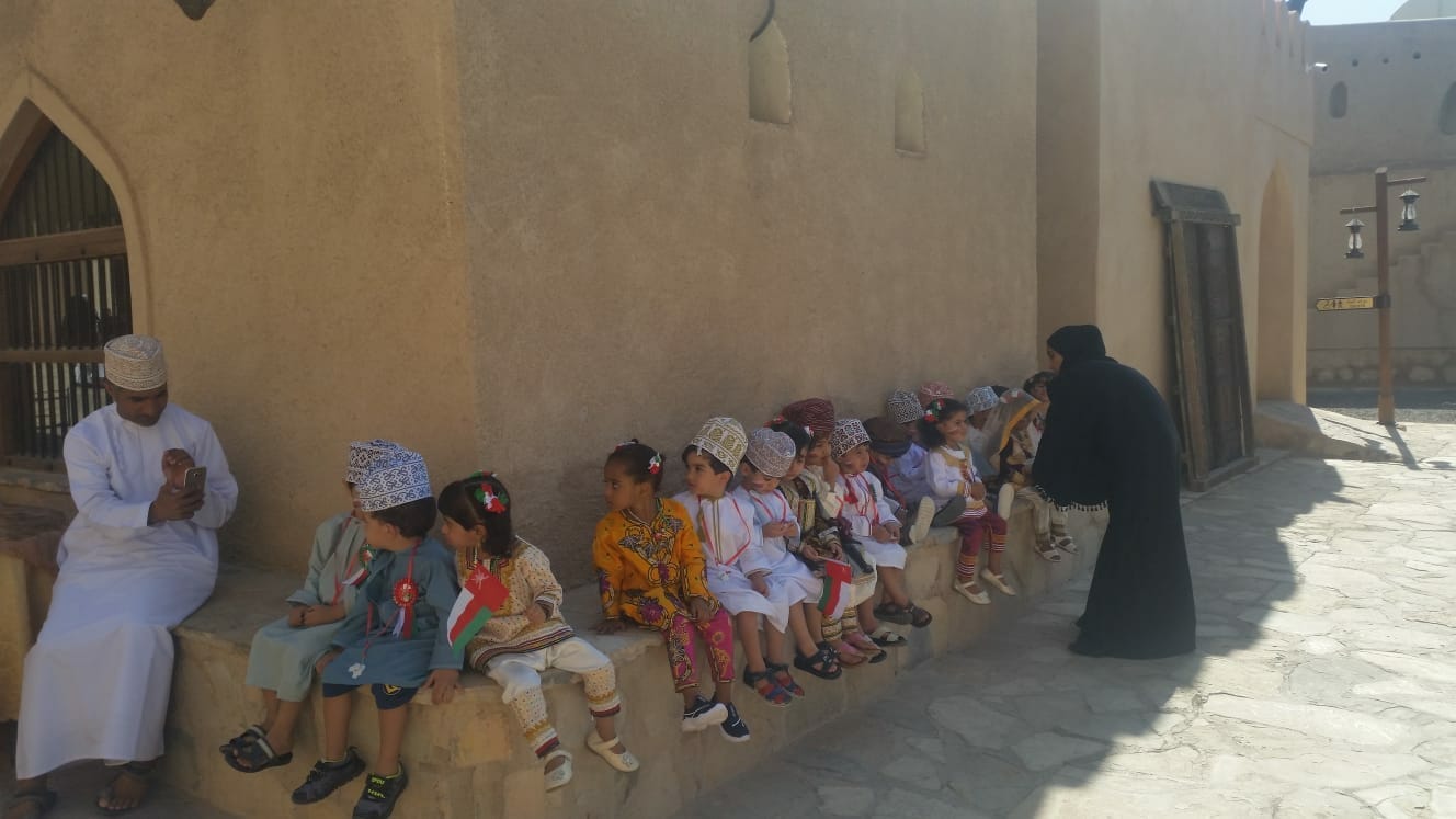 Un grupo escolar en el Fuerte de Nizwa, muchos de los niños y sus maestros llevan vestido tradicional omaní