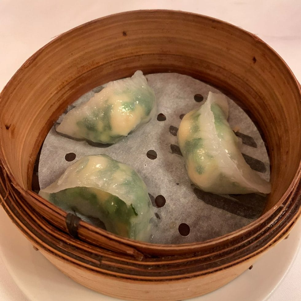 Three prawn and chive dumplings in a bamboo steamer