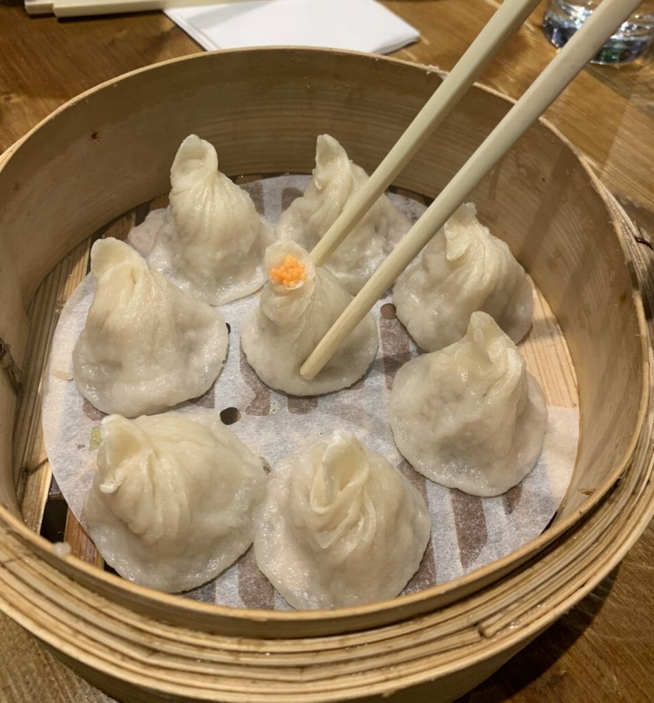 Soup filled Ziao Long Bao dumplings in a steamer with chopsticks