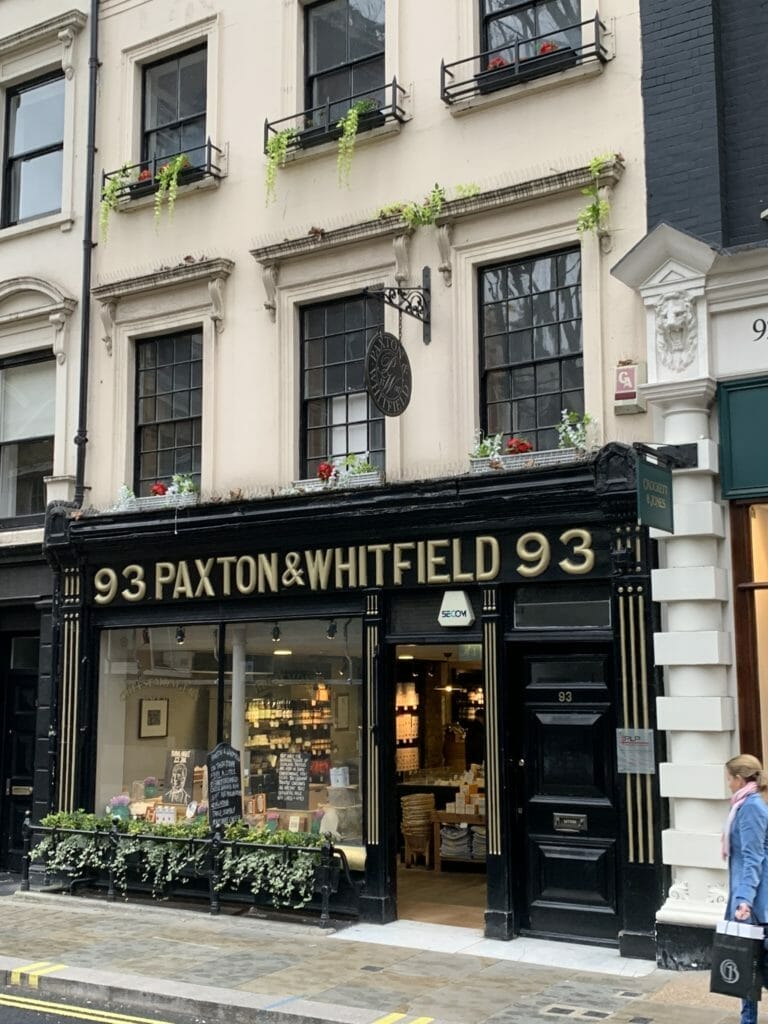 The exterior of Paxton and Whitfield with its black wood paneling and gilt lettering