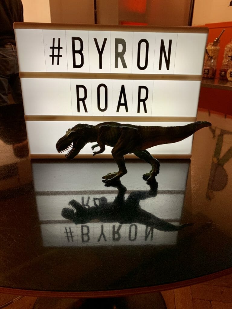 Katie's T-Rex toy stalking the B-Rex in front of the #ByronRoar sign