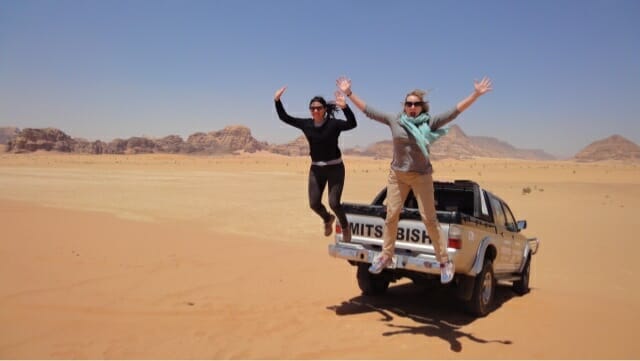 Katie and friend jumping off the truck in the desert near Wadi Rum - What to wear as a woman in Jordan