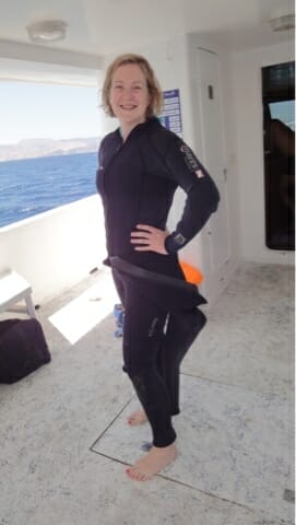 Katie posing on the boat in 1.5 wetsuits