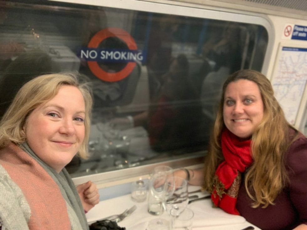 Katie and friend wearing scarfs at their table on the tube