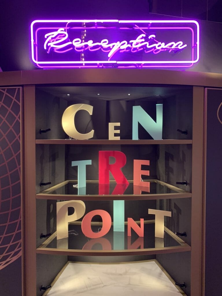 Neon reception sign and display of wooden letters reading Centre Point