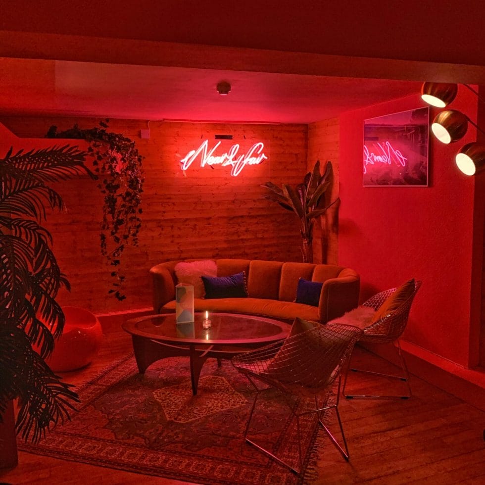 The neon sign lights up the sofa seating area with a pink glow in this private area