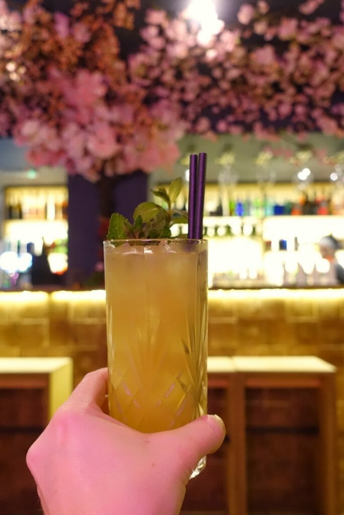 The Foreign Mint cocktail in front of the floral bar
