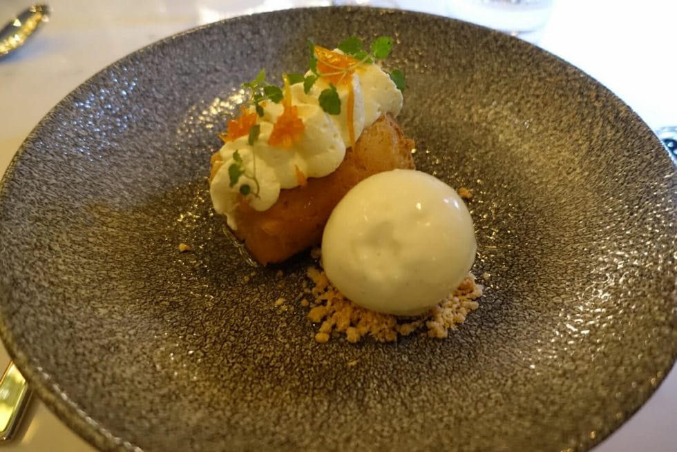 The rum baba with cream and ice cream, garnished with mint and orange peel