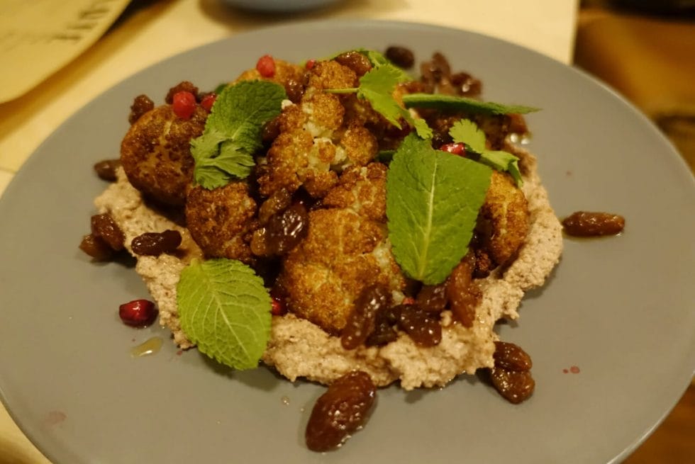 Cumin roasted cauliflower head presented on a walnut paste, with a pretty garnish of mint and pomegranate 