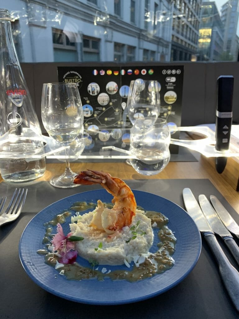 Jumbo prawn sitting on the cauliflower risotto, decorated with a green sauce and edible flowers
