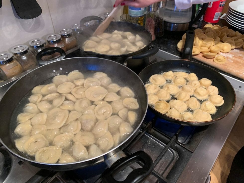 Pans full of dumplings cooking on the stove