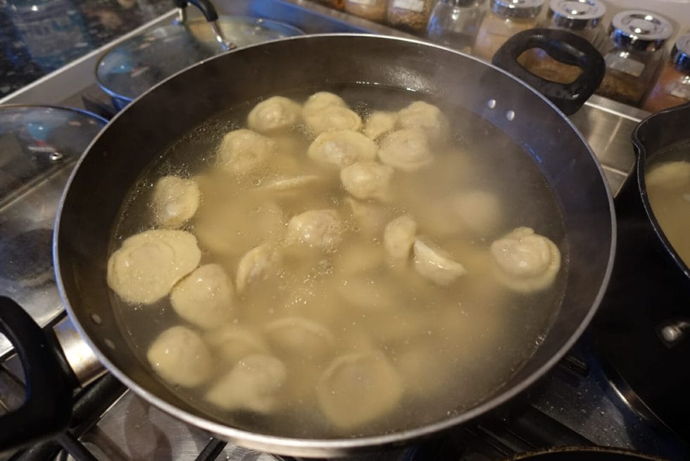 Boiled dumplings in stock - starting to float to the top as they cook through