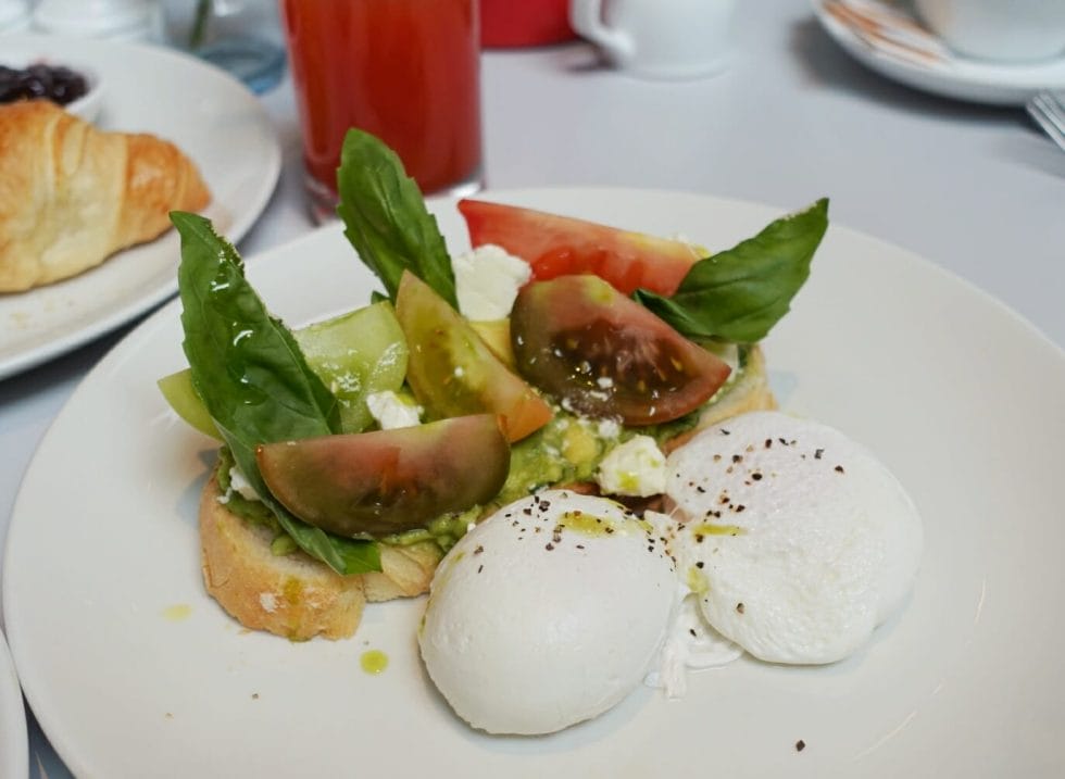 Avocado on toast with poached eggs, heritage tomatoes and fresh basil