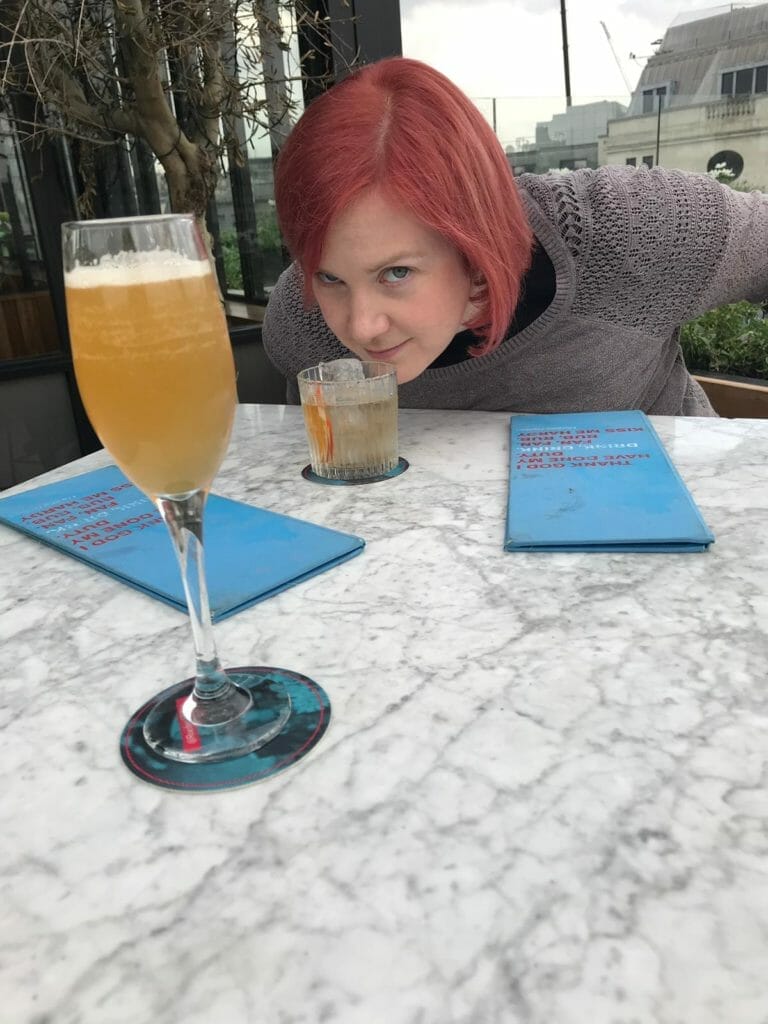 Katie sniffing her negroni, with Lauras champagne cocktail in front
