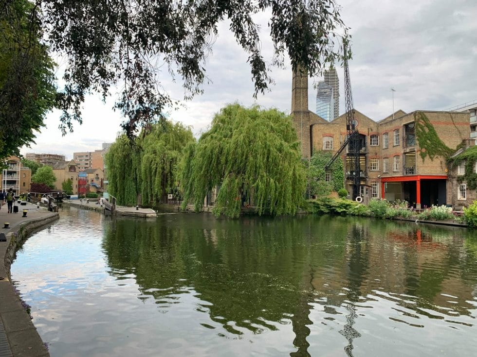 A turning pond in the canal with weeping willows and industrial buildings in the background