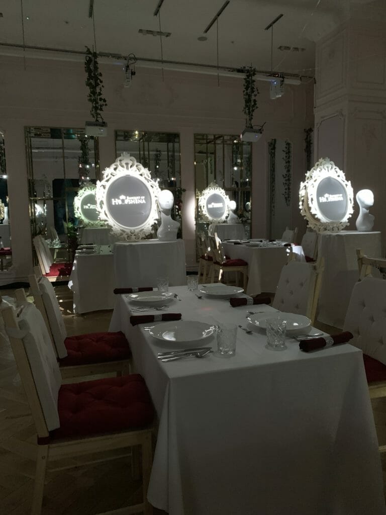 White table-clothed tables with 'mirror's lit up by each