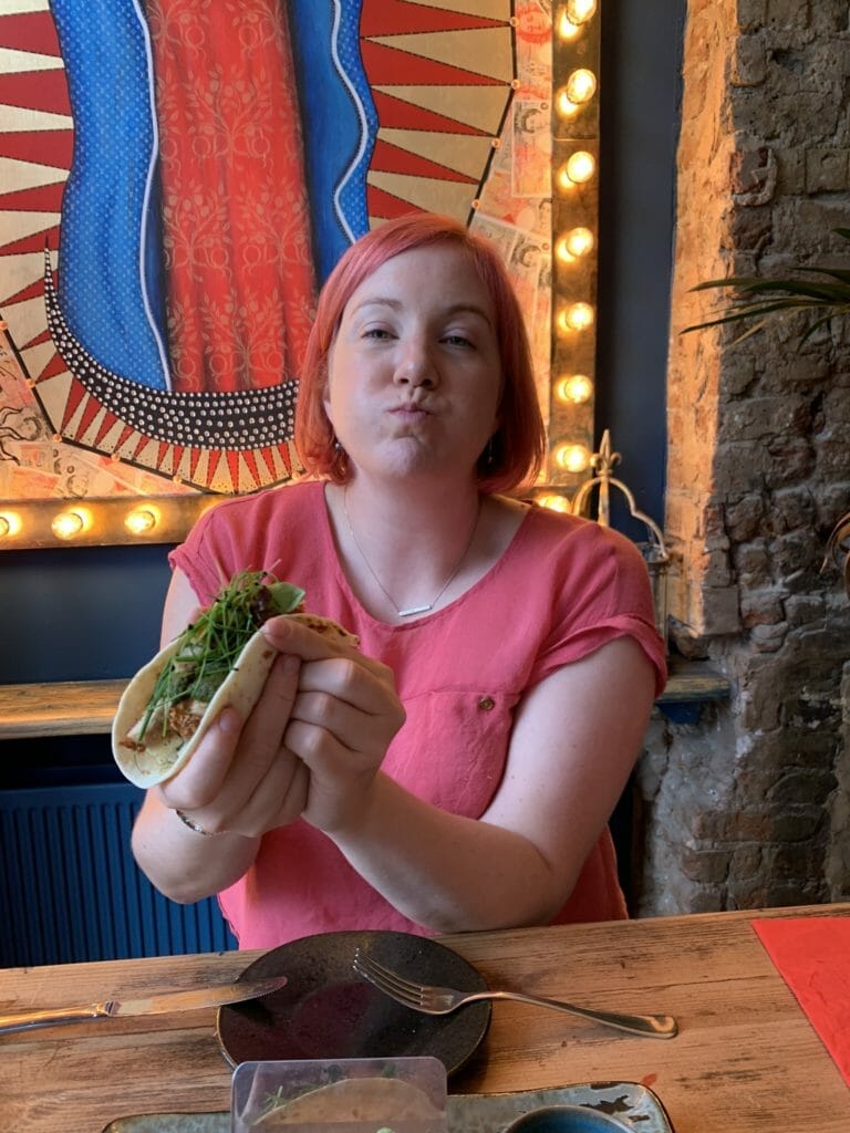 Katie holding taco with mouth full