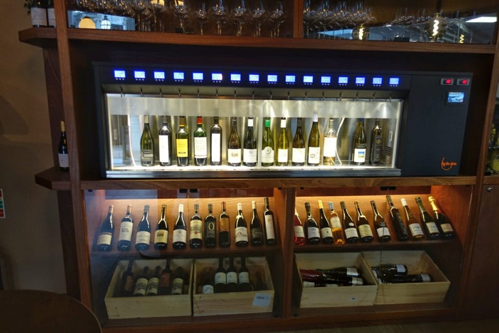Enomatic machine above the wine shelves with bottles available by the glass