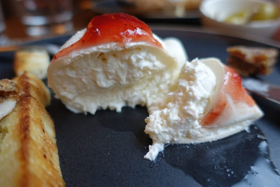 Close up of the cut open burrata with jam on top