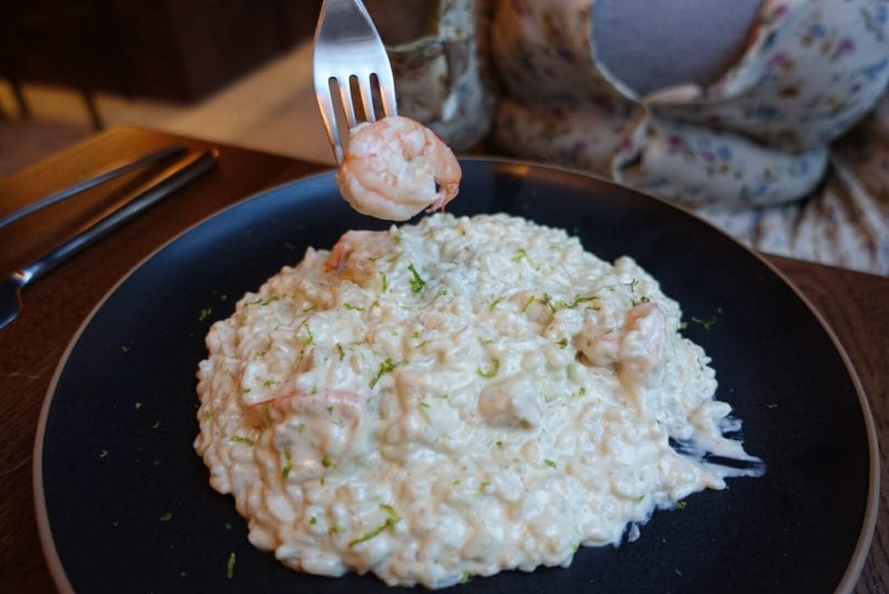 White risotto with lime zest and king prawn on a fork