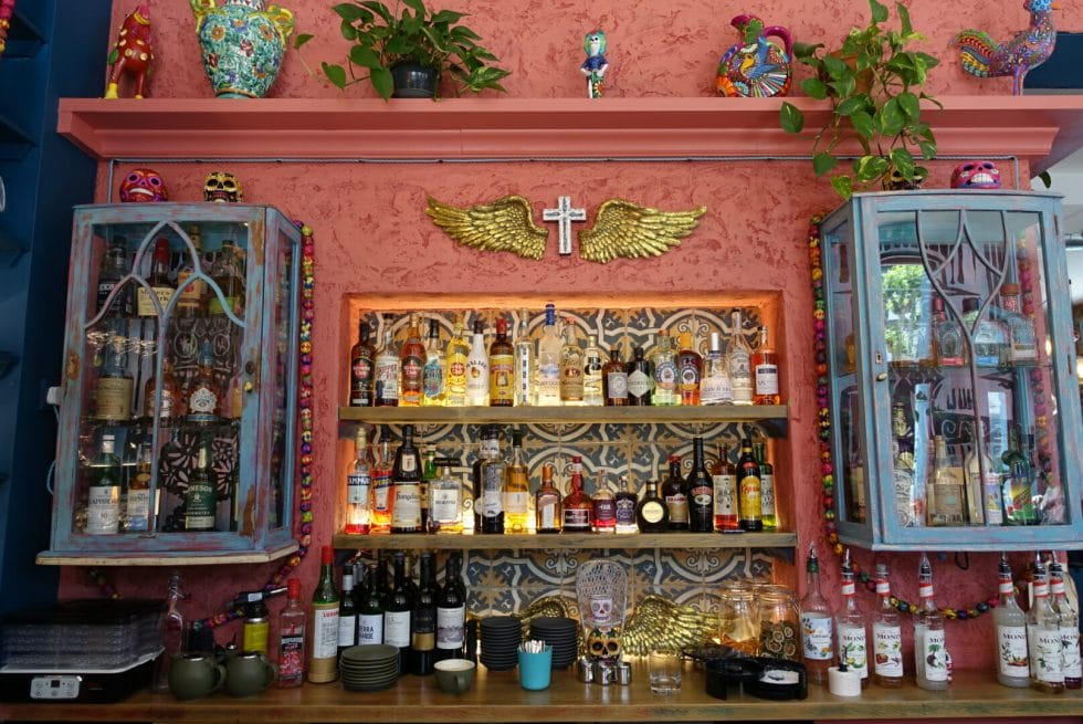 Back bar lit up with lots of Mexicana decorations and a salmon pink wall