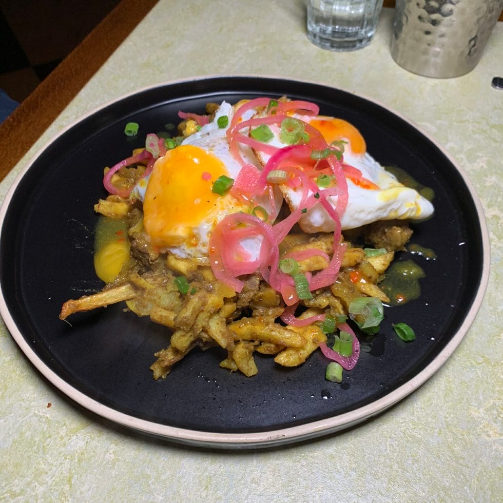 Curry goat hash with potato and fried eggs