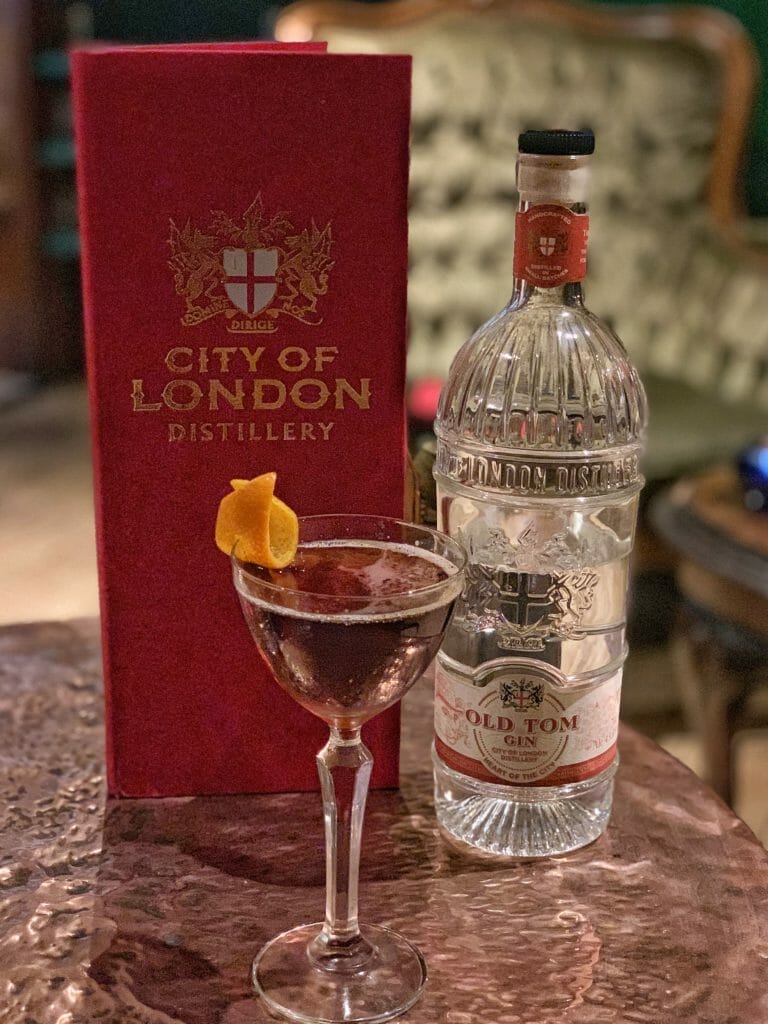 Martinez cocktail in delicate glass in front of COLD menu and Old Tom gin bottle