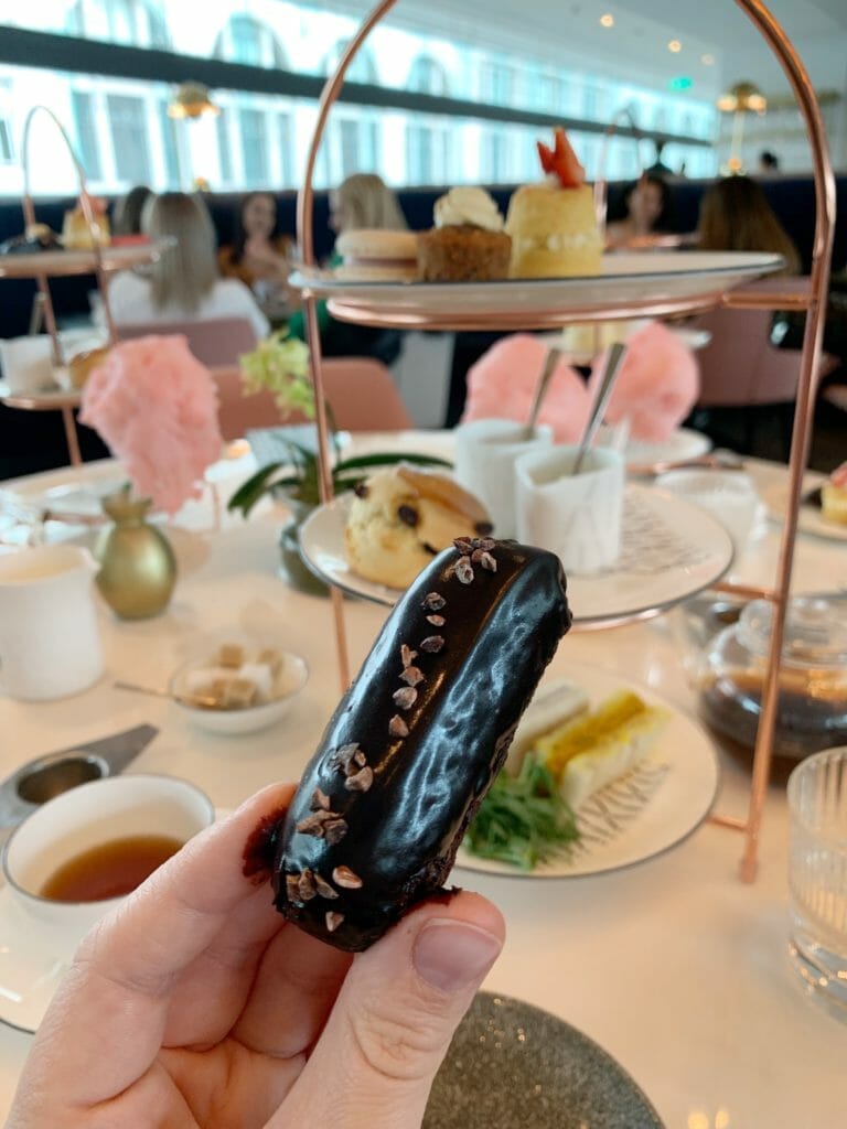 Chocolate eclair held up in front of the cake stand