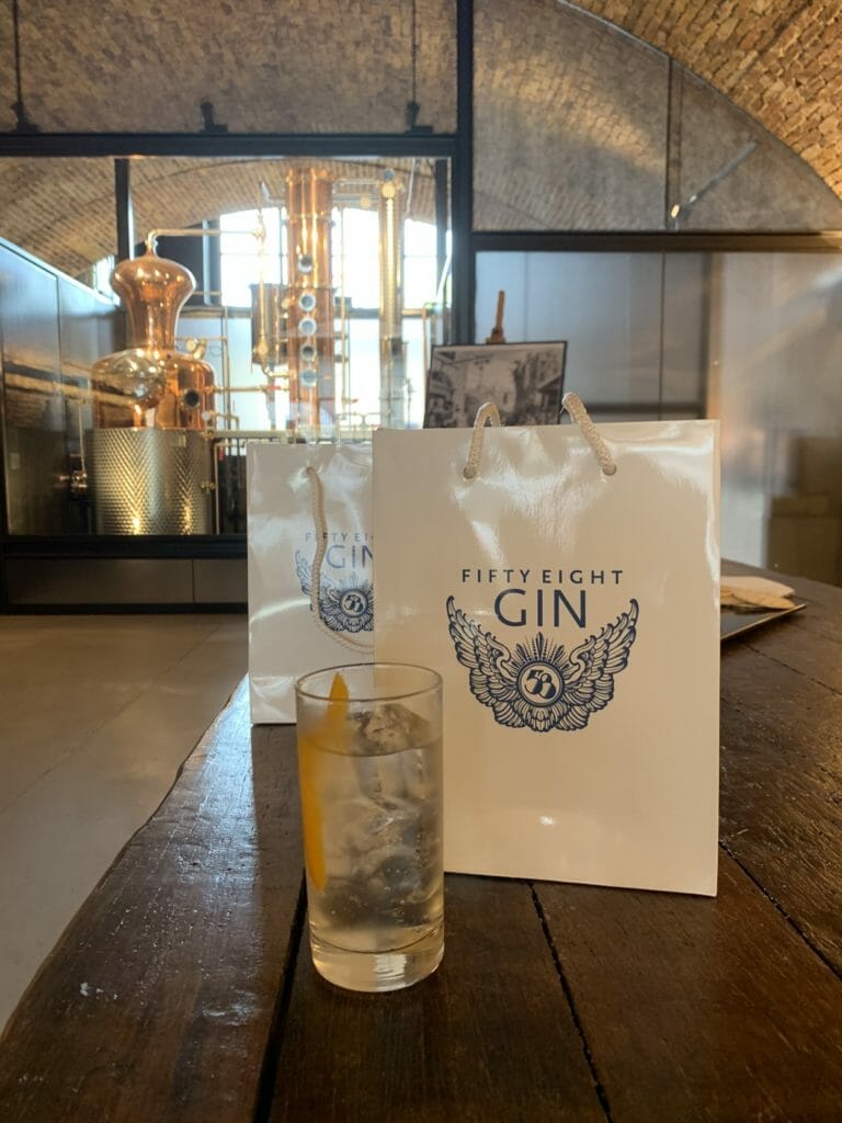 Gin and tonic in front of a 58 Gin branded bag with the still in the background