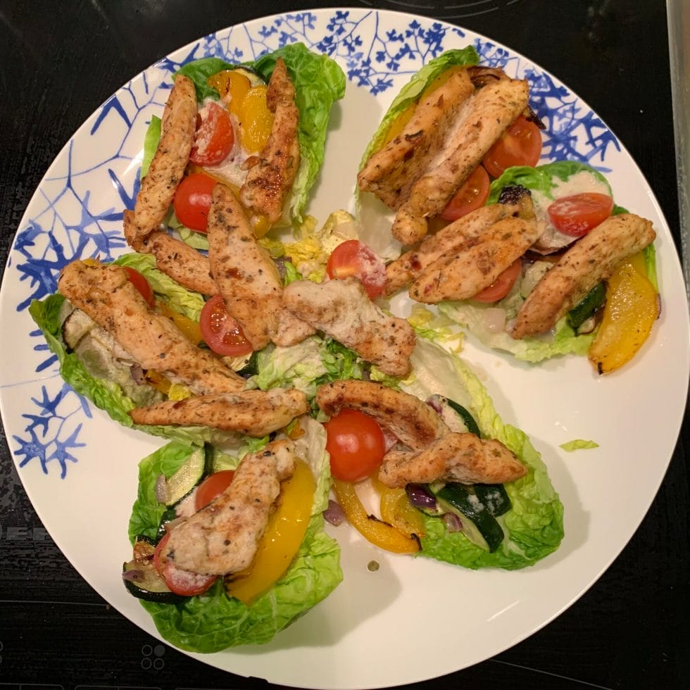 Plate with chicken and roasted veggies on lettuce leaves