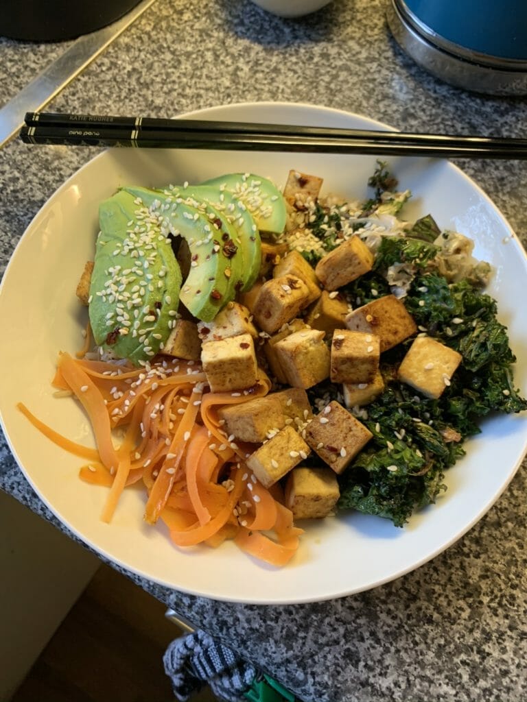 Bowl of bibimbap with tofu, avocado veggies with chopsticks