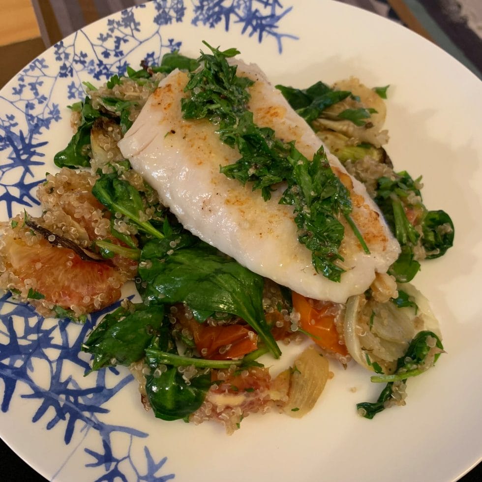 White fish on top of a quinoa salad with a herb sauce