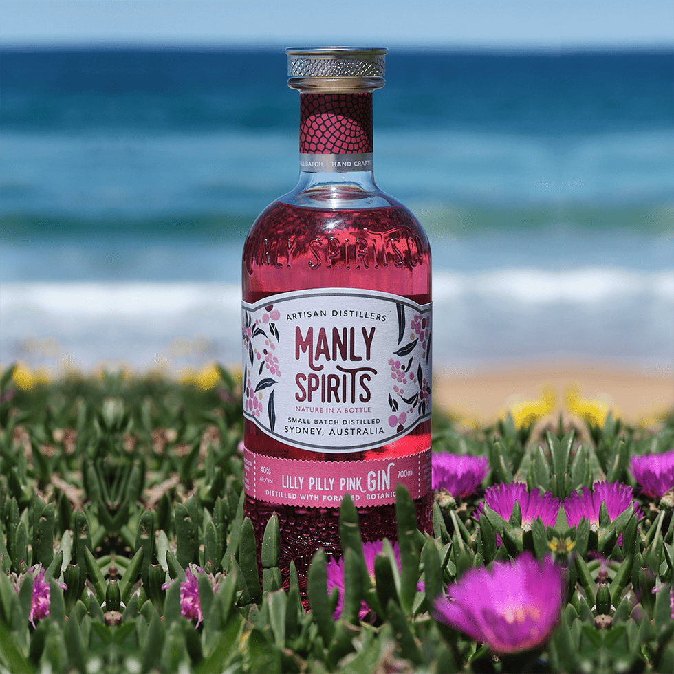 Manly bottle with pink flowers and succulent plants by the beach