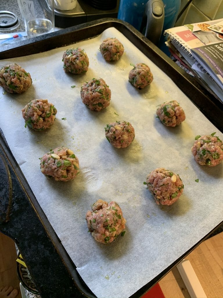 Meatballs lined up on a baking tray ready to go in the oven
