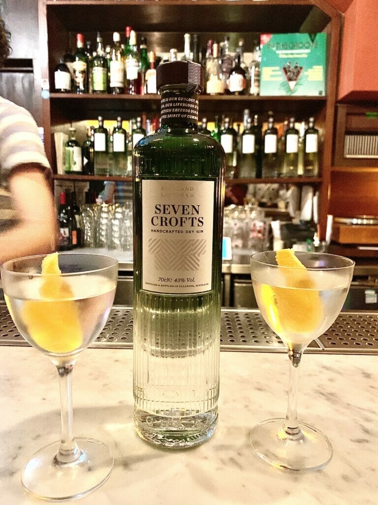Seven Crofts gin bottle on a bar with two martini glasses