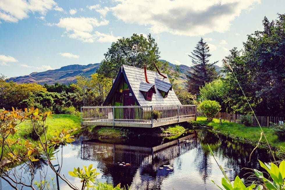 The Fairy Tale Distillery on a pond surrounded by green with mountains in the background