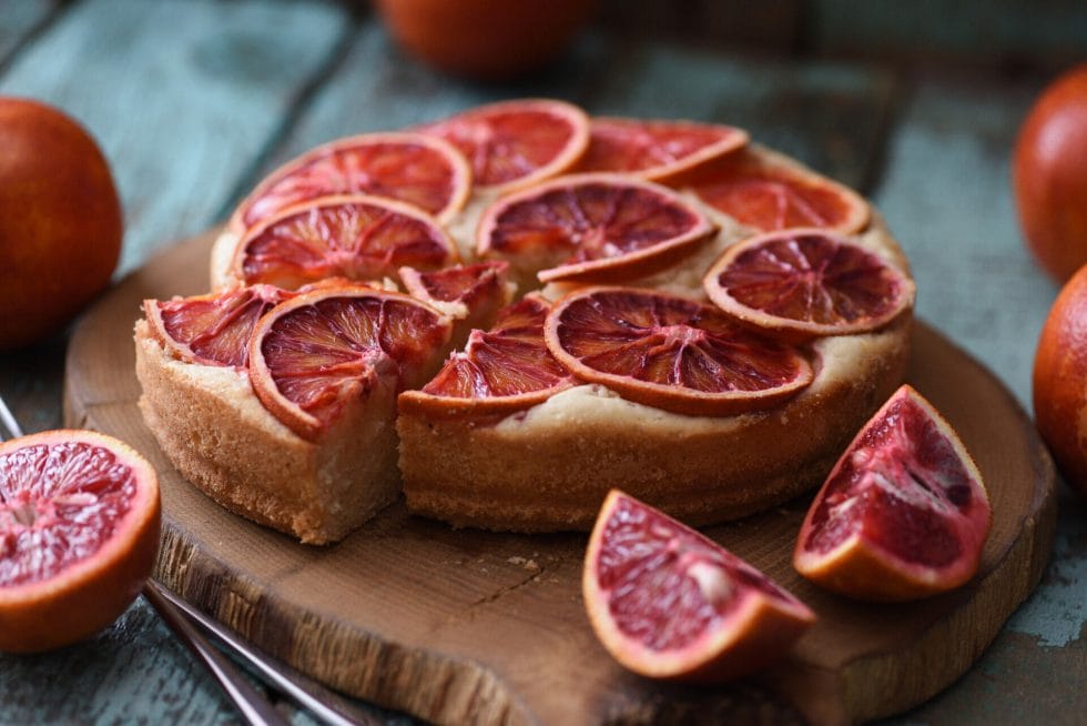 Blood orange slices on cake served on oak board closeup