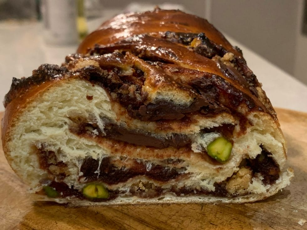 Cut open baked babka, showing date and chocolate and pistachios